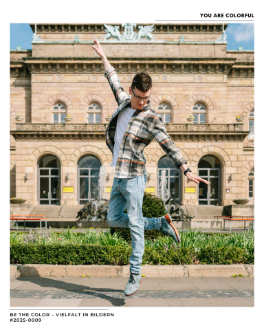 Junger Mann tanzt vor einem historischen Gebäude, trägt lässige Kleidung und Sneakers.